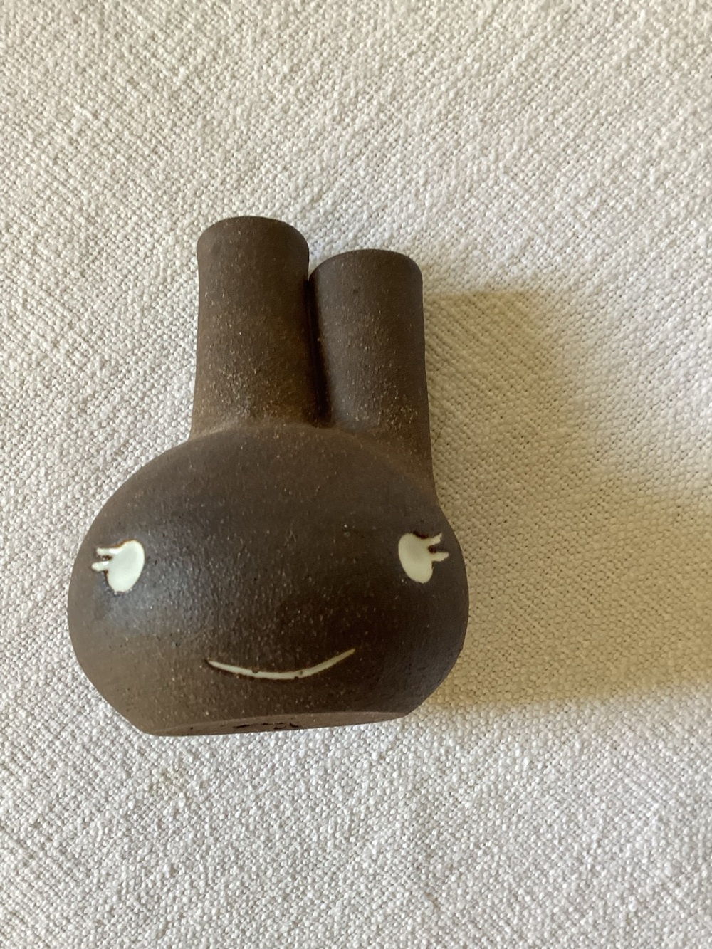 whimsical brown ceramic bud vase featuring a playful face with white-painted eye